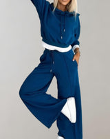 Woman in blue jogger set, hoodie and wide-leg pants, sporty, comfortable, fashionable.