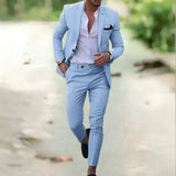Man in light blue suit, white shirt, black shoes, stylish menswear, outdoor.